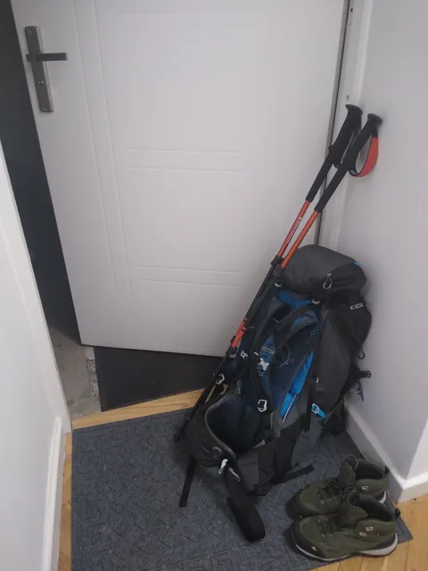 Composición flat-lay con mochila, bastones de trekking y zapatillas de aproximación